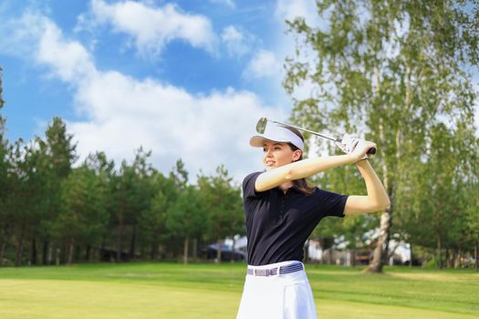 Woman golfer hits an fairway shot towards the club house