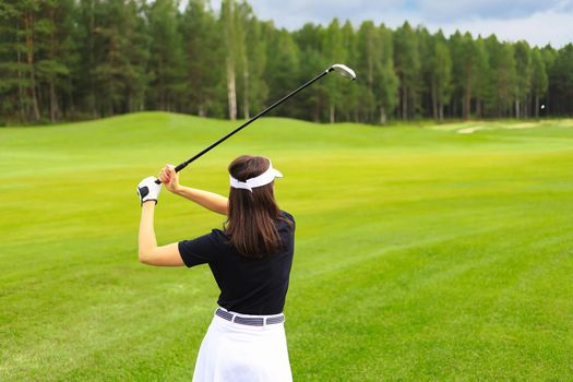 Woman golfer hits an fairway shot towards the club house