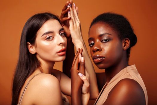 young pretty asian, afro woman posing cheerful together on brown background, lifestyle diverse nationality people concept cloe up