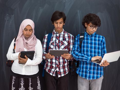 Modern Arab teens use smartphones, tablets, and laptops to study during online classes due to corona virus pandemic. High quality photo