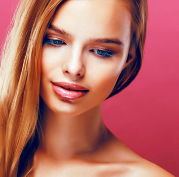 young pretty blonde real woman with hairstyle close up and makeup on pink background smiling close up