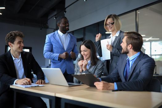 Happy business people laugh near laptop in the office. Successful team coworkers joke and have fun together at work