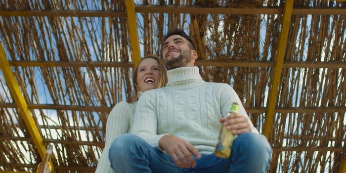 Couple Drinking Beer Together on beach during autumn time