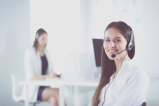 Smiling businesswoman or helpline operator with headset and computer at office.