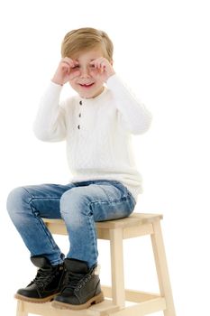 A cute little boy is sitting on a chair. Isolated on white background.