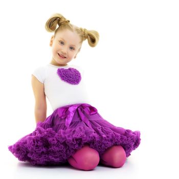 Beautiful little girl kneels in the studio on a white background. The concept of beauty and fashion, children's emotions. Isolated.