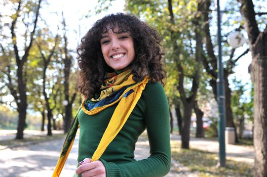 brunette Cute young woman with colorful scarf smiling outdoors in nature
