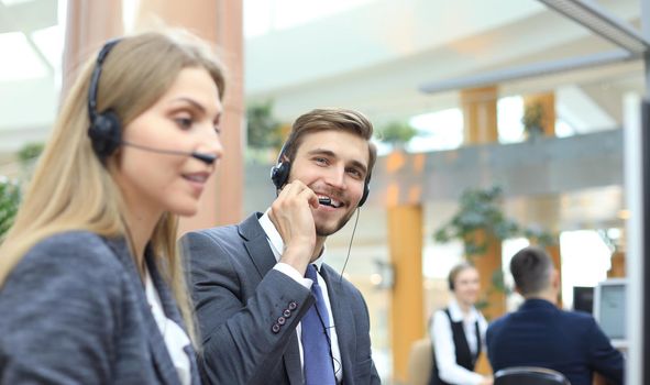 Portrait of call center worker accompanied by his team. Smiling customer support operator at work