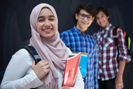 Arabic teenagers, students group  portrait against black chalkboard wearing backpack and books in school