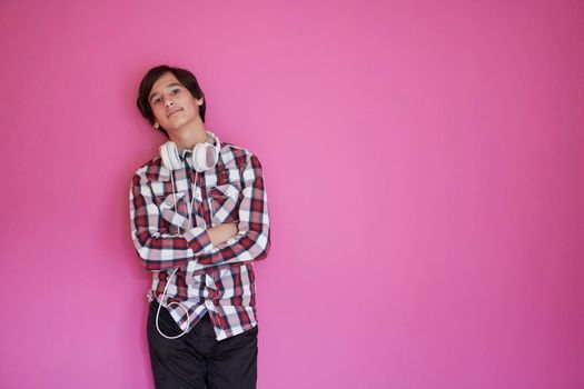 arab teenager with wearing  casual school look against pink background wearing headphones