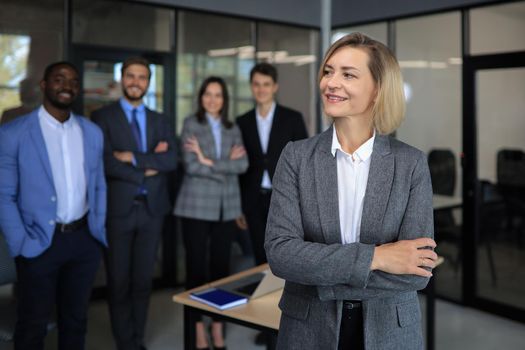 Business woman with her staff, people group in background at modern bright office indoors