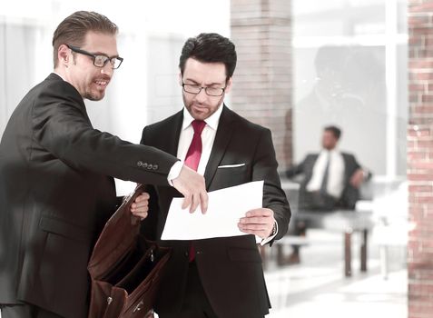 business partners discuss the document standing in the office lobby.the concept of business relationship