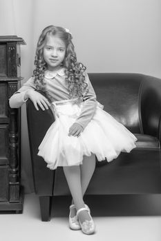 Little girl is sitting on the couch in the room. The concept of a happy childhood.