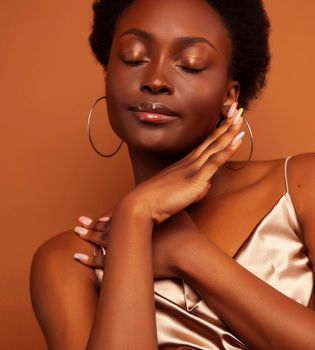 pretty young african american woman with curly hair posing cheerful gesturing on brown background, lifestyle people concept close up