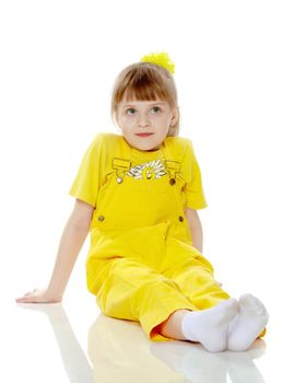 Girl with a short bangs on her head and bright yellow overalls.She crouched down on the white advertising banner.