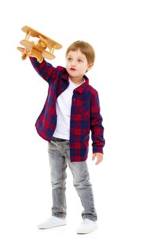 Happy kid boy plays with wooden toy airplane.Isolated on white background.