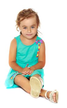 Little girl is sitting on the floor. The concept of a happy childhood. Isolated on white background.