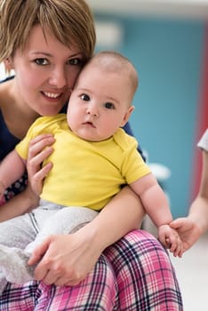 Portrait of young happy mother holding newborn baby boy while sitting on the sofa at home