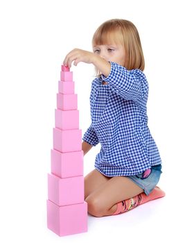 Cute little girl in Montessori in kindergarten working with a pink pyramid.