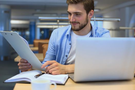 Portrait of young man sitting at his desk in the office