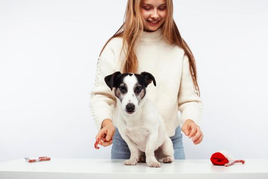 pretty young blond girl with her little cute dog wearing Santas red hat at Christmas holiday isolated on white background, lifestyle people concept close up