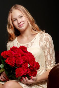 Beautiful young teen girl with a bouquet of flowers. Studio photo on a black background. The concept of style and fashion.