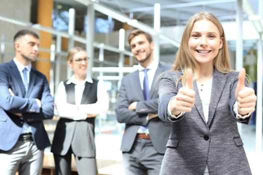 business concept - attractive businesswoman with team in office showing thumbs up