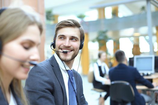 Portrait of call center worker accompanied by his team. Smiling customer support operator at work