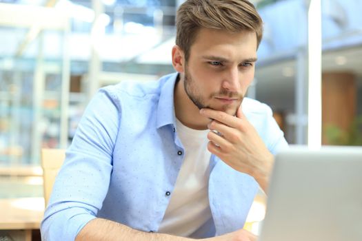 Portrait of young man sitting at his desk in the office