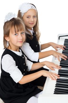 2 cute little girls play in four hands on the piano - Isolated on white background