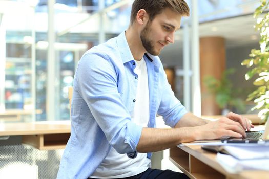 Portrait of young man sitting at his desk in the office