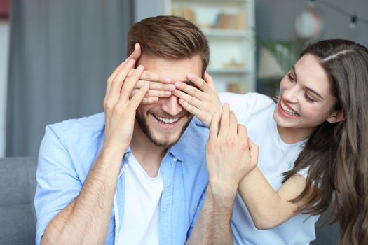 Young cute woman covering her husband's eyes