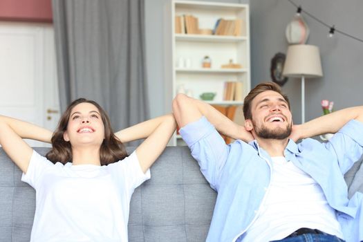 Smiling beautiful couple sitting on a sofa and dreaming about new home