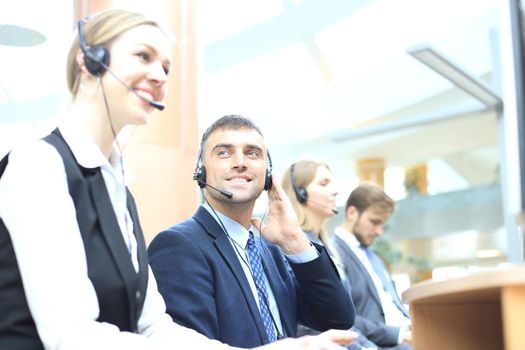 Portrait of call center worker accompanied by his team. Smiling customer support operator at work