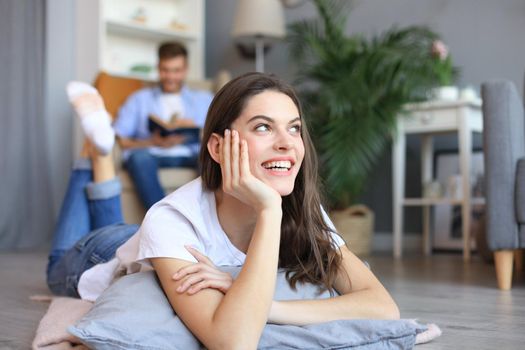 Portrait of attractive woman relaxing on floor with blurred man in background