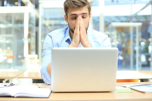 Portrait of young man sitting at his desk in the office