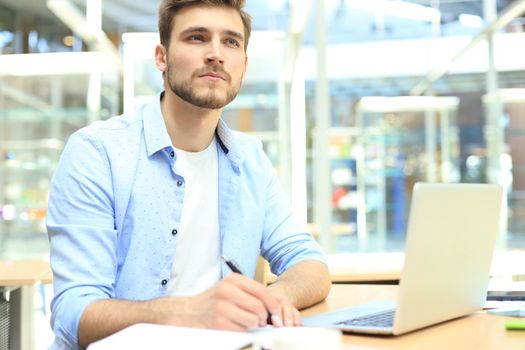 Portrait of young man sitting at his desk in the office