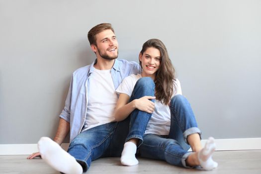 The happy couple sitting on the background of the gray wall