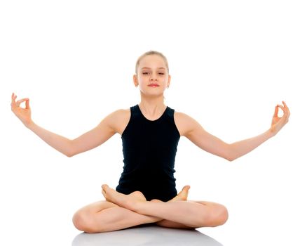 A nice little girl sits in a lotus position and meditates. Concept of yoga, happy people. Isolated on white background.