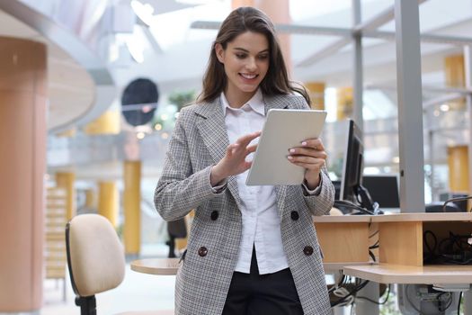 Young smiling businesswoman in office working on digital tablet