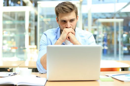 Portrait of young man sitting at his desk in the office