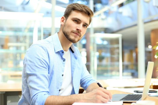 Portrait of young man sitting at his desk in the office