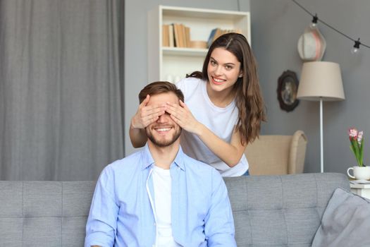 Young cute woman covering her husband's eyes