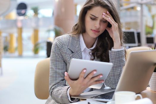 Portrait of tired business lady working with touchpad in office