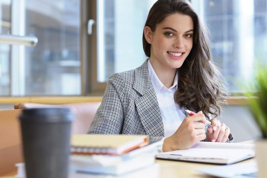 Portrait of a pretty female student with laptop in library