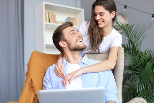 Young couple doing some online shopping at home, using a laptop on the sofa