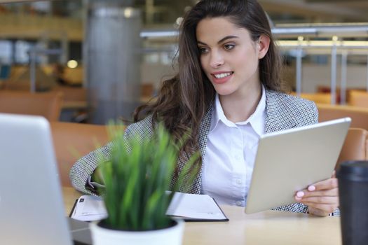 Young smiling businesswoman in office working on digital tablet