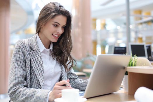 Portrait of a young brunette business woman using laptop at office
