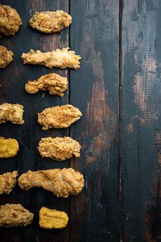 Homemade crispy fried chicken parts on old dark wooden table, top view, with copy space.