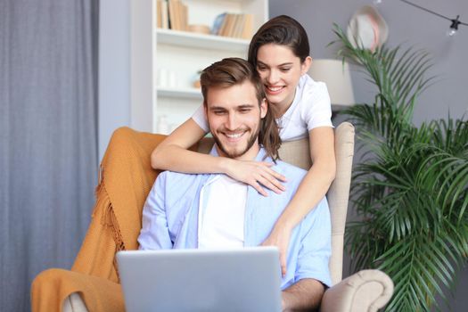 Young couple doing some online shopping at home, using a laptop on the sofa